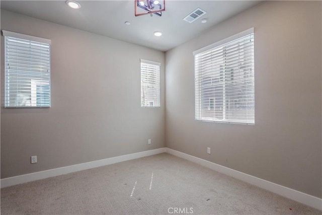 spare room featuring light carpet, visible vents, recessed lighting, and baseboards