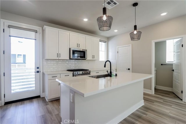 kitchen with visible vents, a sink, tasteful backsplash, appliances with stainless steel finishes, and light wood finished floors