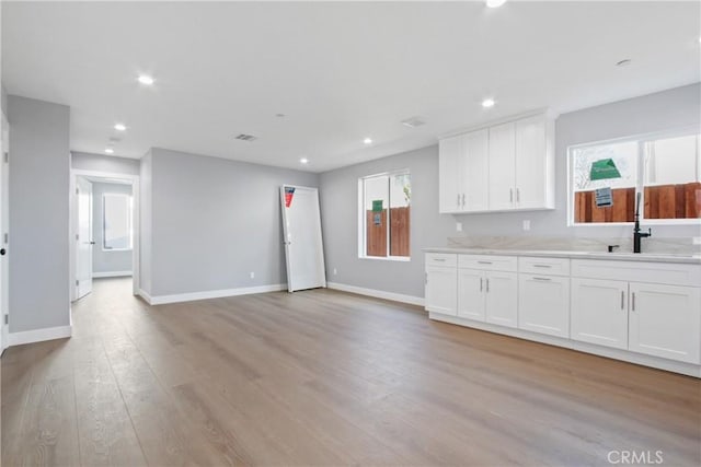 kitchen featuring a sink, light wood-type flooring, white cabinets, and recessed lighting