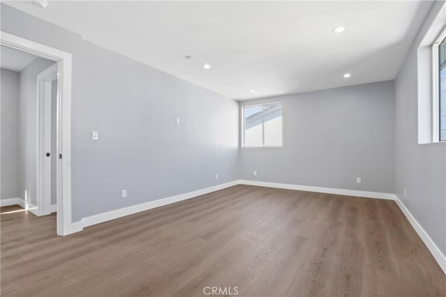 empty room featuring recessed lighting, wood finished floors, and baseboards