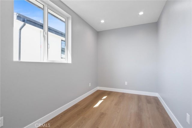 empty room with recessed lighting, wood finished floors, and baseboards