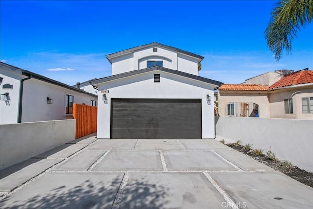 view of front of house featuring stucco siding, an attached garage, concrete driveway, and fence