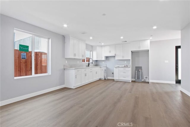 kitchen featuring a sink, light wood-type flooring, baseboards, and recessed lighting