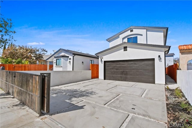 view of front of property featuring driveway, a garage, a fenced front yard, and stucco siding