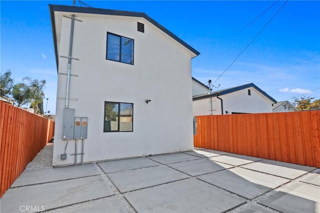 rear view of property with a patio area, a fenced backyard, and stucco siding