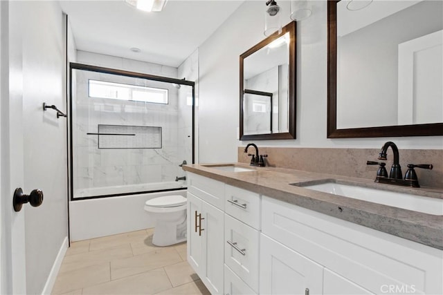 bathroom featuring a sink, toilet, double vanity, and combined bath / shower with glass door