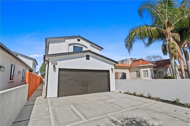 view of front of house with a tiled roof, a fenced front yard, concrete driveway, and stucco siding