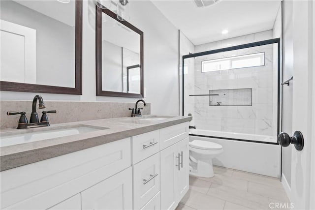 full bath with a sink, combined bath / shower with glass door, toilet, and double vanity