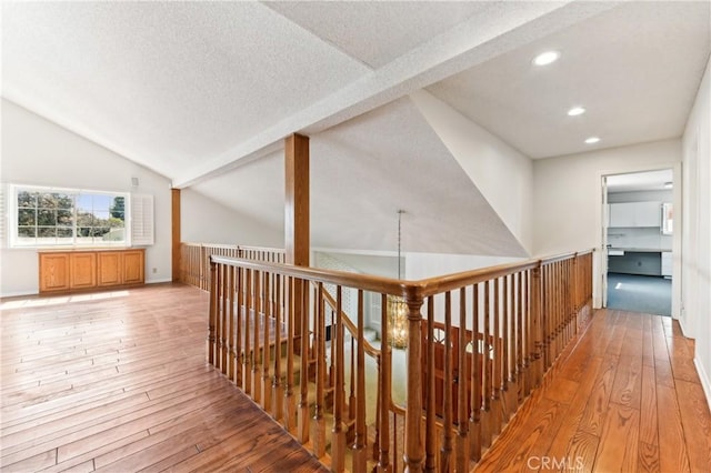 hallway featuring recessed lighting, a textured ceiling, vaulted ceiling with beams, and light wood-type flooring