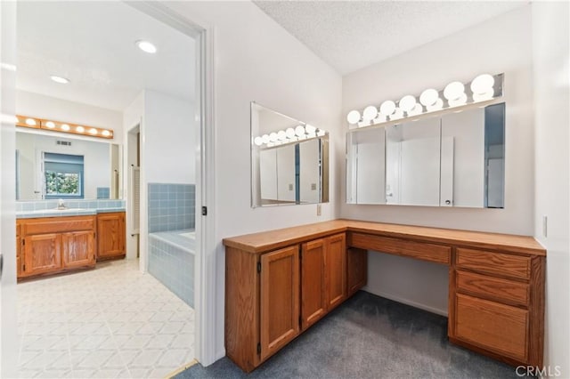 full bath with a textured ceiling, vanity, and a tub to relax in