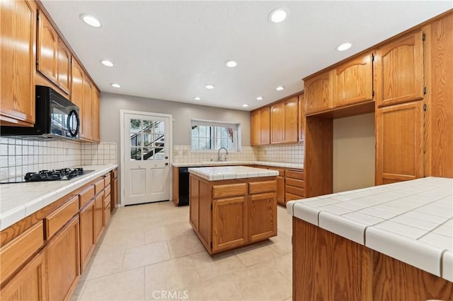 kitchen with a sink, tasteful backsplash, black appliances, and tile countertops