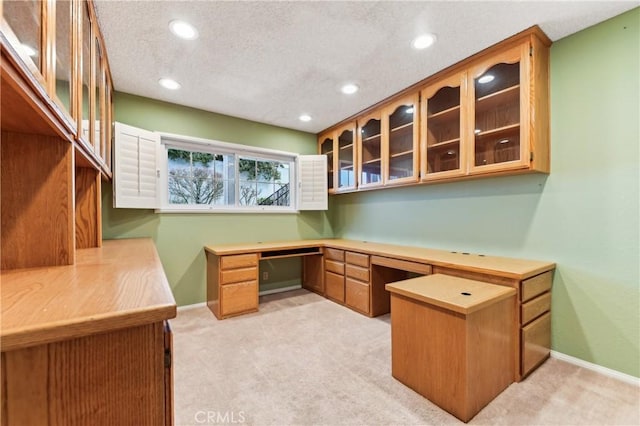 home office featuring light carpet, baseboards, and built in study area