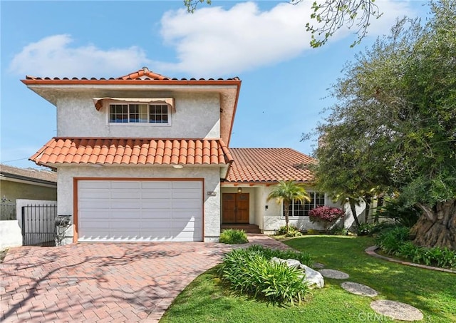 mediterranean / spanish home featuring fence, a front yard, stucco siding, decorative driveway, and an attached garage