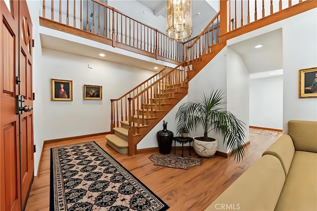 foyer entrance featuring a towering ceiling, light wood-style flooring, and stairs