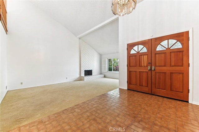 carpeted entrance foyer with a fireplace, a chandelier, and high vaulted ceiling