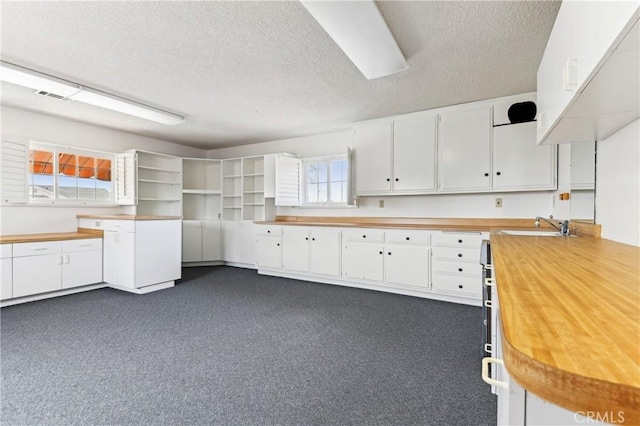 kitchen featuring visible vents, open shelves, a textured ceiling, white cabinetry, and butcher block counters