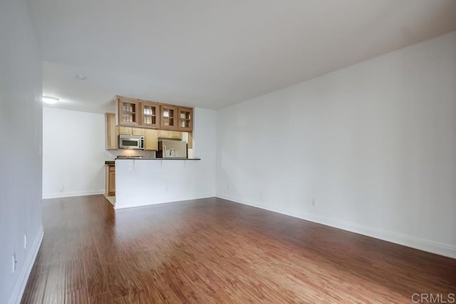 unfurnished living room with dark wood-type flooring and baseboards