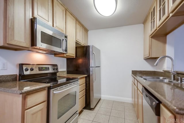 kitchen with a sink, appliances with stainless steel finishes, light brown cabinets, and light tile patterned floors