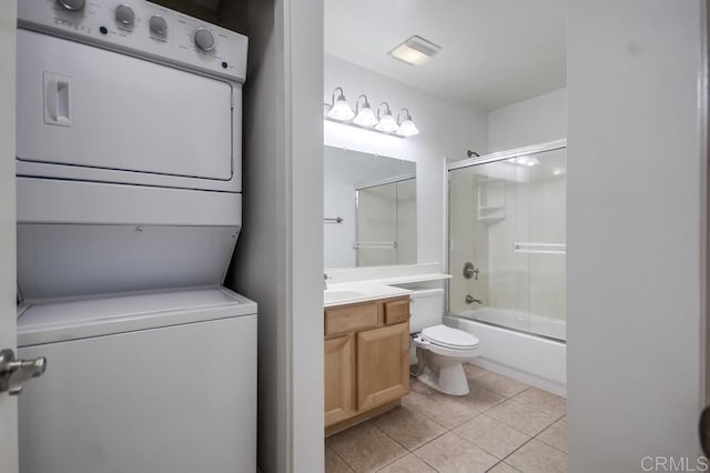 bathroom featuring stacked washer / drying machine, toilet, tile patterned floors, vanity, and enclosed tub / shower combo