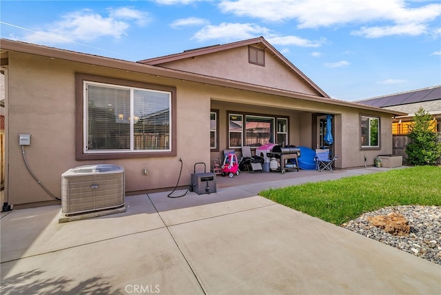 back of property with a patio, central air condition unit, a lawn, and stucco siding