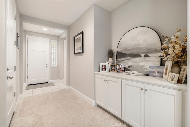 hallway featuring light tile patterned floors, baseboards, and light carpet