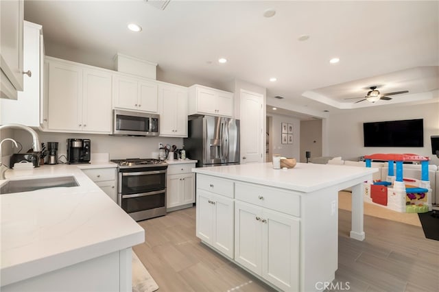 kitchen featuring open floor plan, recessed lighting, stainless steel appliances, white cabinetry, and a sink