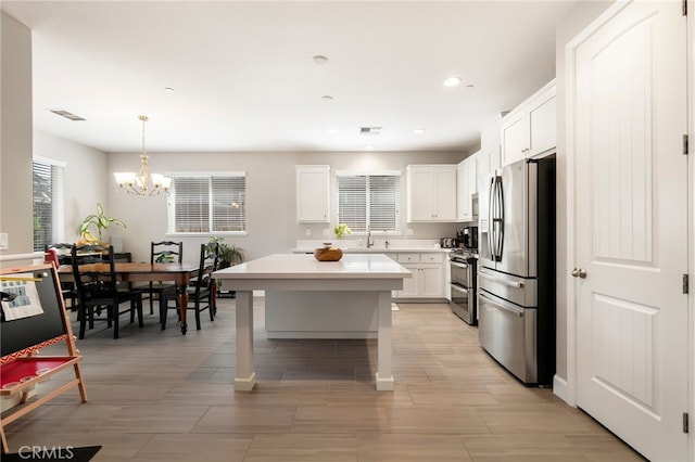 kitchen with visible vents, a sink, white cabinets, appliances with stainless steel finishes, and a chandelier