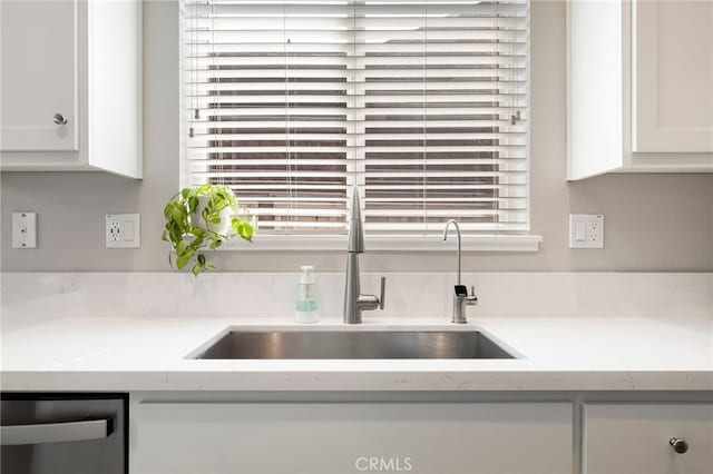 room details featuring white cabinets, dishwasher, light countertops, and a sink