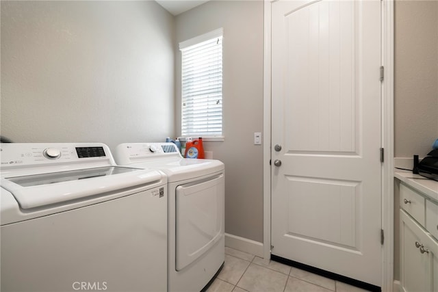 laundry area with light tile patterned floors, baseboards, cabinet space, and washer and clothes dryer