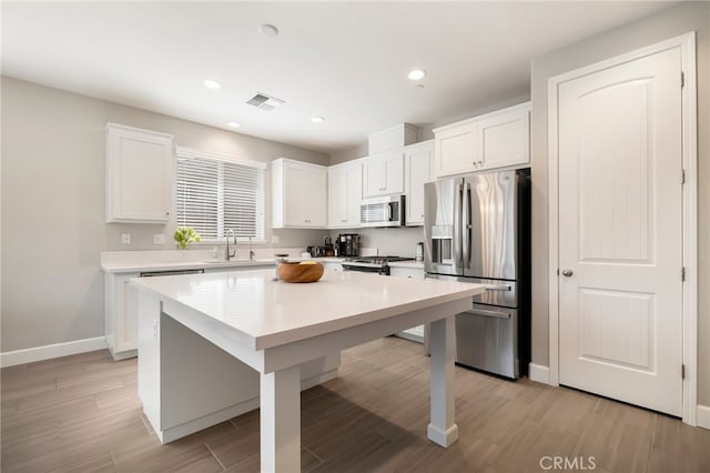 kitchen with visible vents, a sink, stainless steel appliances, light countertops, and white cabinetry