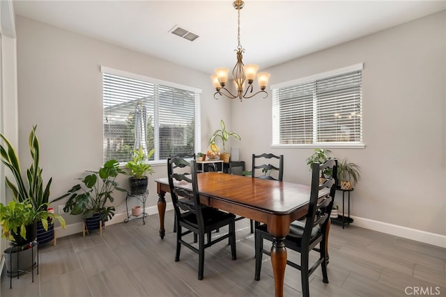 dining room with a notable chandelier, visible vents, light wood-style floors, and baseboards