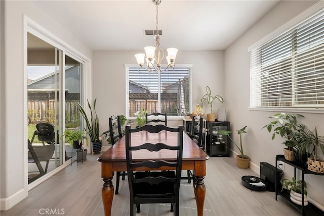 dining area with light wood-style floors, visible vents, baseboards, and a notable chandelier