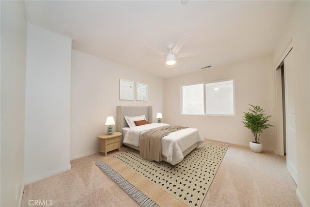 bedroom featuring a ceiling fan, light colored carpet, visible vents, and baseboards