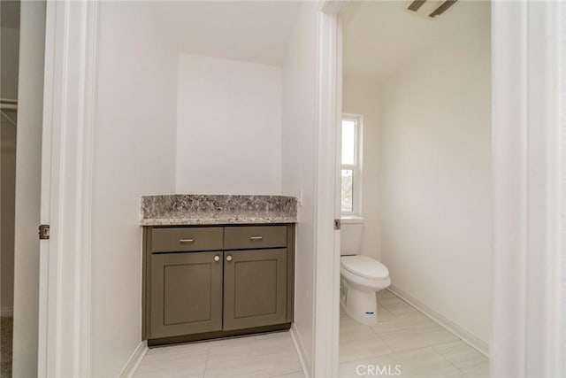 bathroom featuring baseboards, toilet, and vanity