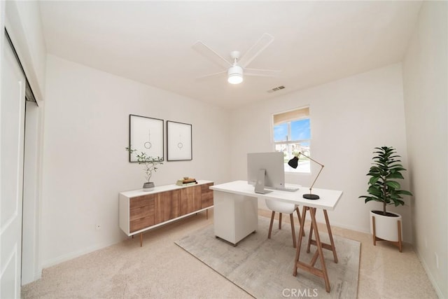 office space with visible vents, light colored carpet, baseboards, and a ceiling fan