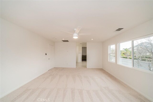 unfurnished room featuring visible vents, baseboards, light colored carpet, and a ceiling fan