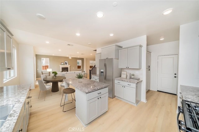 kitchen with light wood finished floors, open floor plan, stainless steel fridge, and a kitchen island