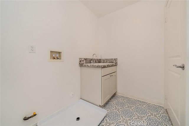 laundry area featuring light tile patterned floors, baseboards, hookup for a washing machine, and a sink