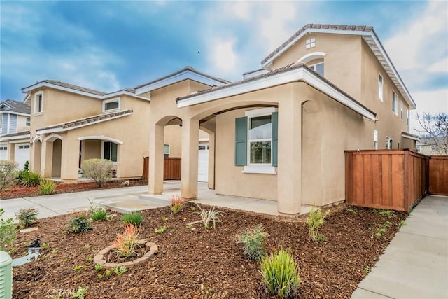 mediterranean / spanish home featuring stucco siding and fence