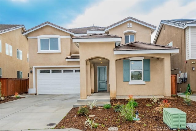 mediterranean / spanish home with stucco siding, a tile roof, fence, concrete driveway, and an attached garage