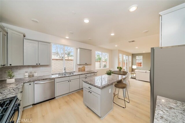 kitchen featuring a sink, a kitchen bar, appliances with stainless steel finishes, and light wood finished floors