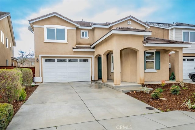 view of front of house featuring a tiled roof, stucco siding, an attached garage, and concrete driveway