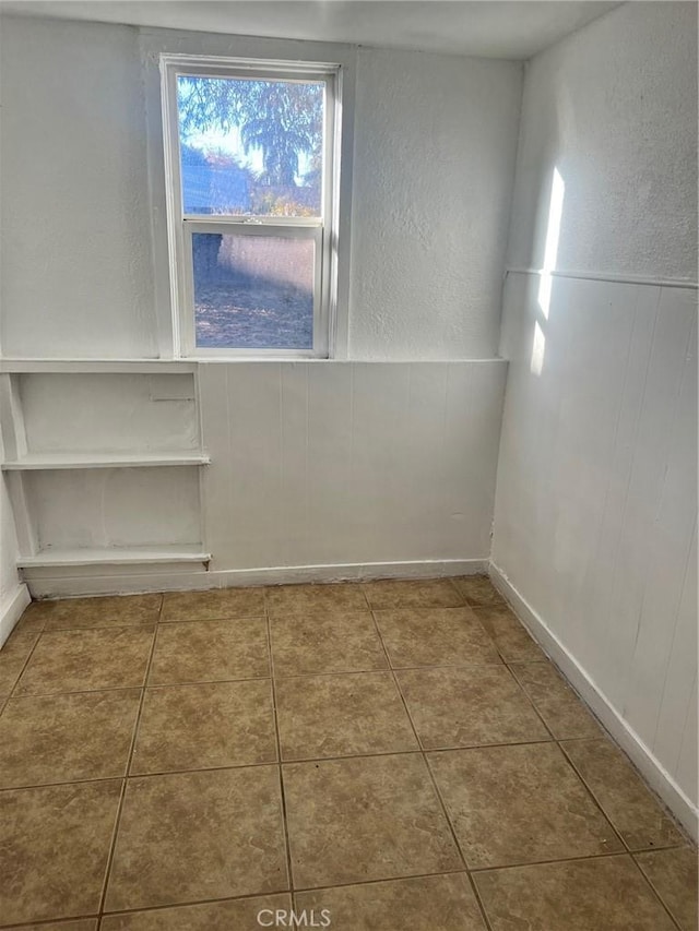 tiled spare room with a textured wall