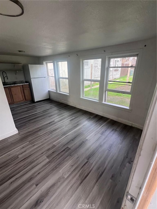 unfurnished living room featuring dark wood-style floors, baseboards, and a textured ceiling