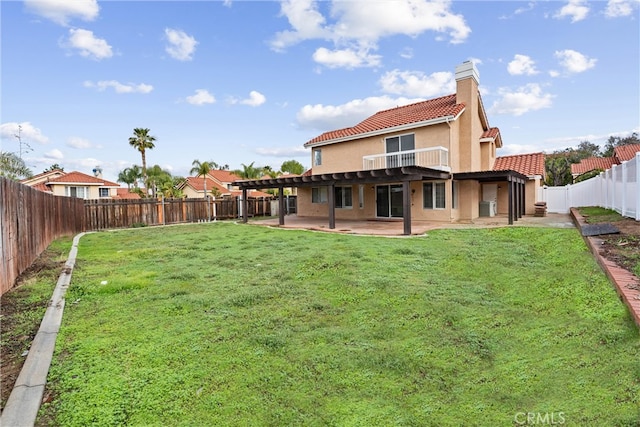 rear view of property featuring a tiled roof, stucco siding, a chimney, a yard, and a patio area