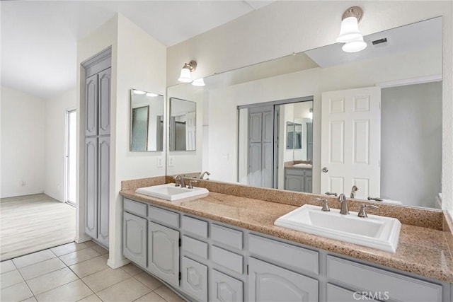 bathroom with tile patterned floors, visible vents, double vanity, and a sink