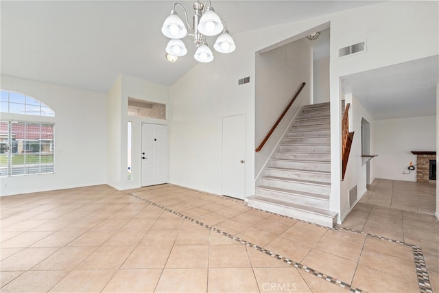 tiled entrance foyer featuring visible vents, high vaulted ceiling, and stairs