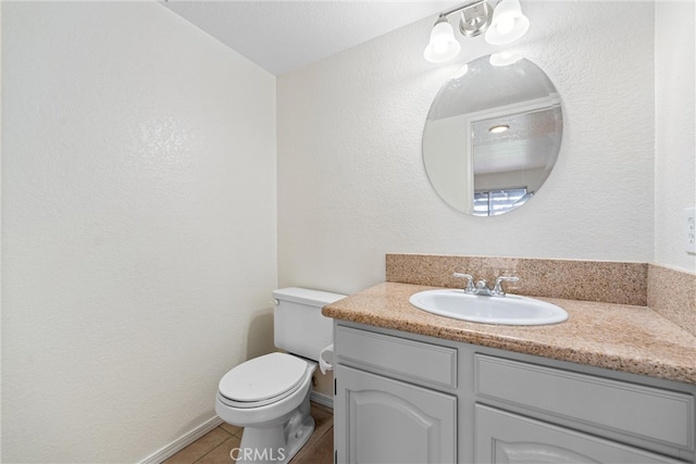 half bathroom with vanity, toilet, baseboards, and tile patterned flooring