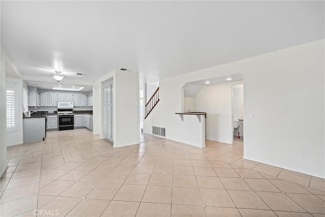 unfurnished living room with stairway, light tile patterned floors, and visible vents