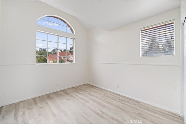 empty room with baseboards, lofted ceiling, and wood finished floors